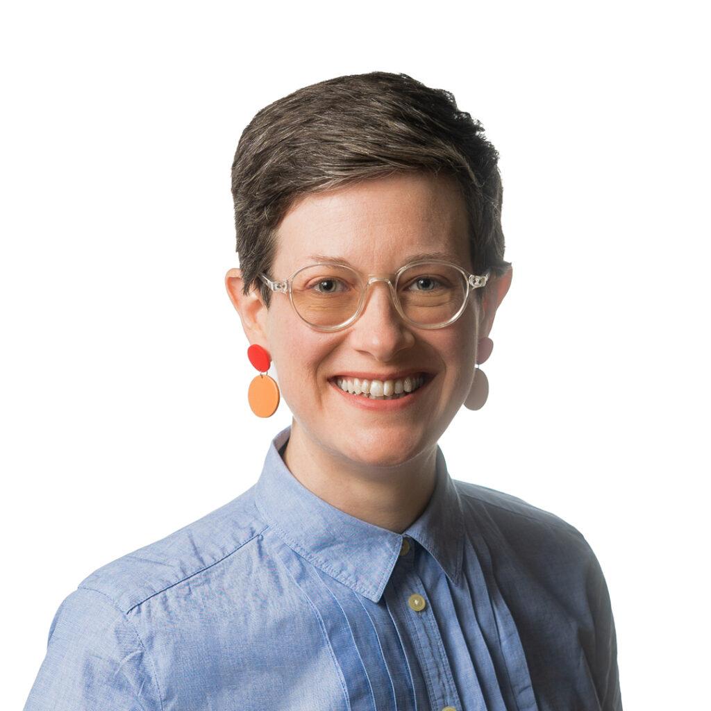 A headshot of a female-presenting person (Rachel Lyons) smiling.